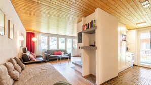 Een woonkamer met een houten plafond, een bank, een salontafel en een open haard.