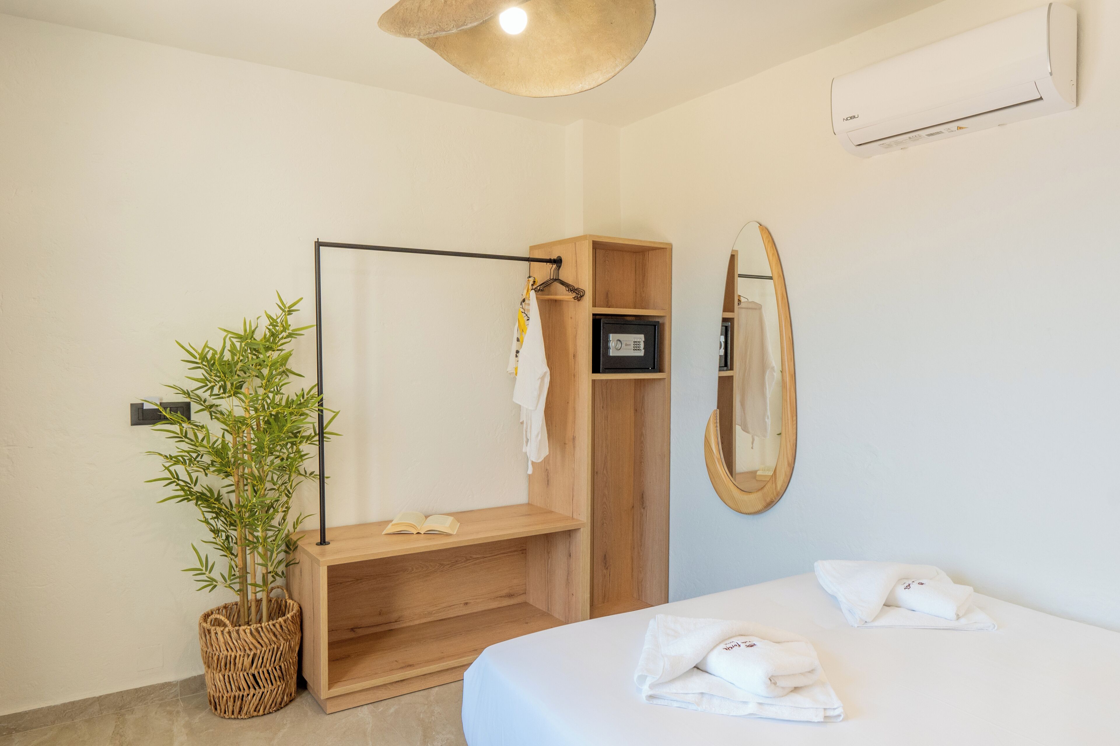 Ein modernes Badezimmer mit Dusche, einem Holzwaschtisch, einem Spiegel und einem Nachttisch mit Handtüchern.