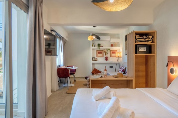 Une chambre d’hôtel comprenant un lit, un bureau, une chaise, une lampe et une étagère avec divers objets.