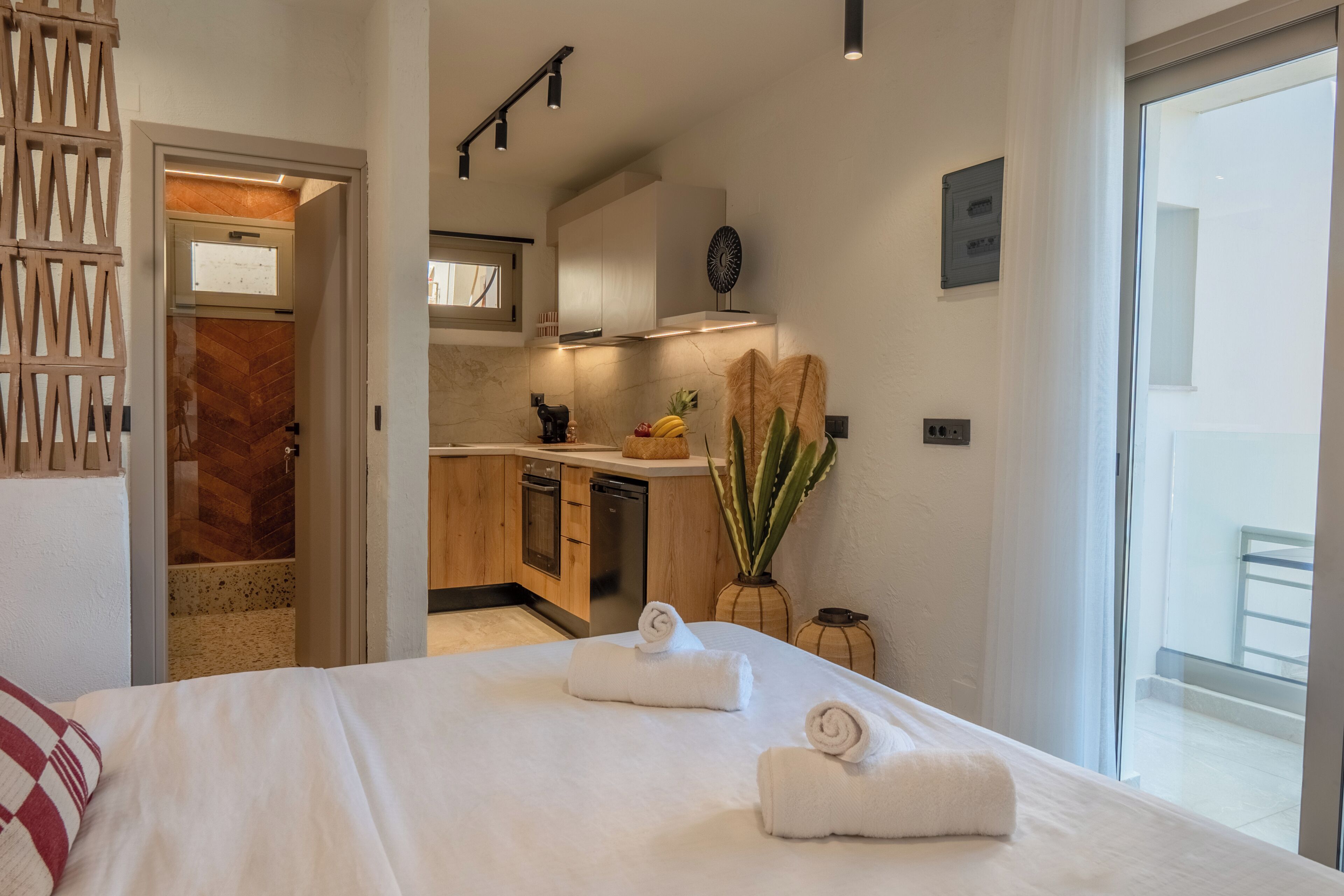 Habitación de hotel con cama, vista a la cocina y un balcón.