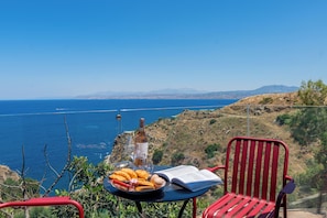 Ein Tisch mit einem Buch, einer Flasche und einer Schüssel Essen mit Blick auf die Küste.