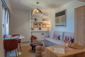 Un salon moderne avec un canapé, une table à manger et des chaises, une lampe et une bouteille de vin.