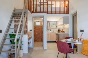 A modern interior with a staircase, a kitchen with wooden cabinets, and a dining area with red chairs. - Soluna Forte Sea Living Suites (Malevizi)