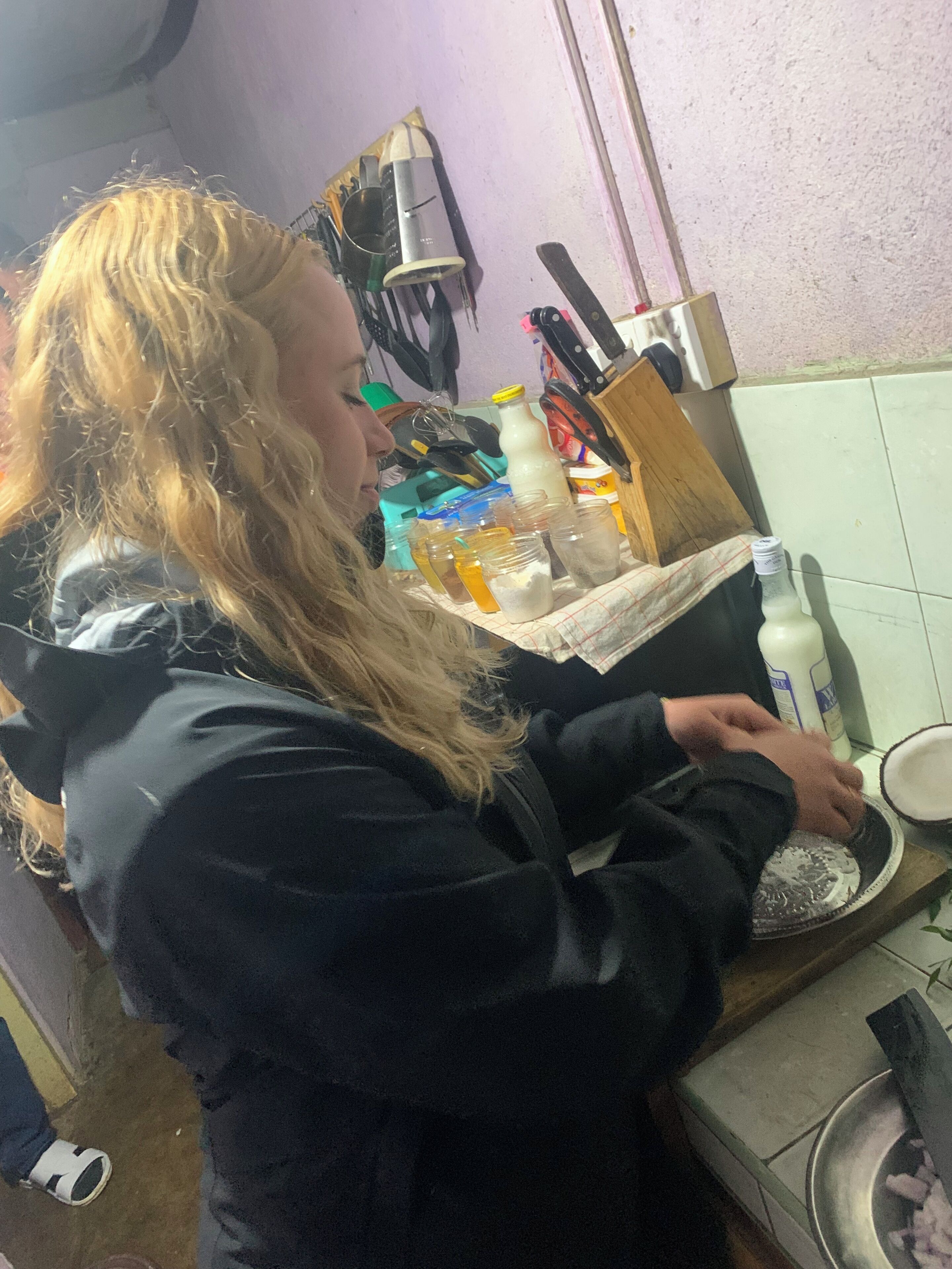 A person in a kitchen with a counter, various kitchen utensils, and containers.