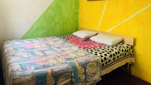 Una habitación con una cama, una pared verde y amarilla, y un cuadro enmarcado sobre la cama.