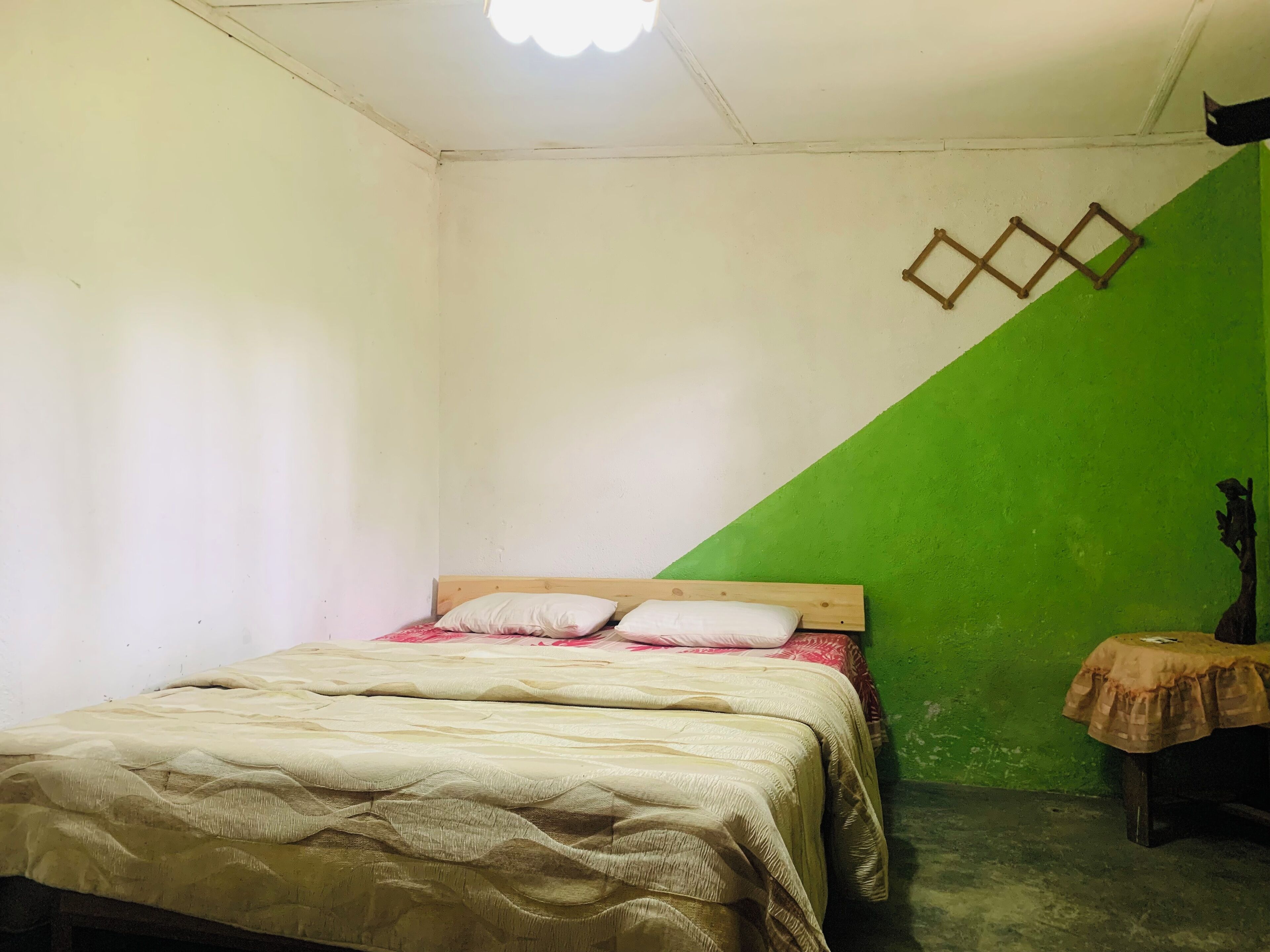 Une chambre à coucher avec un lit, une table de chevet et un mur vert.