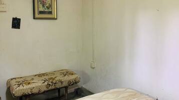 A room with a bed, a bench, and two framed pictures on the wall.