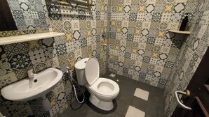 A bathroom with a toilet, sink, and shower. The walls are tiled with a floral pattern.