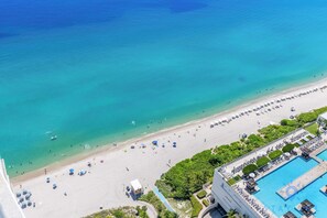 An aerial view of a beach resort with a swimming pool, beach umbrellas, and a clear blue sea. - Hollywood 2BR Apartment w/Balcony (Hollywood)