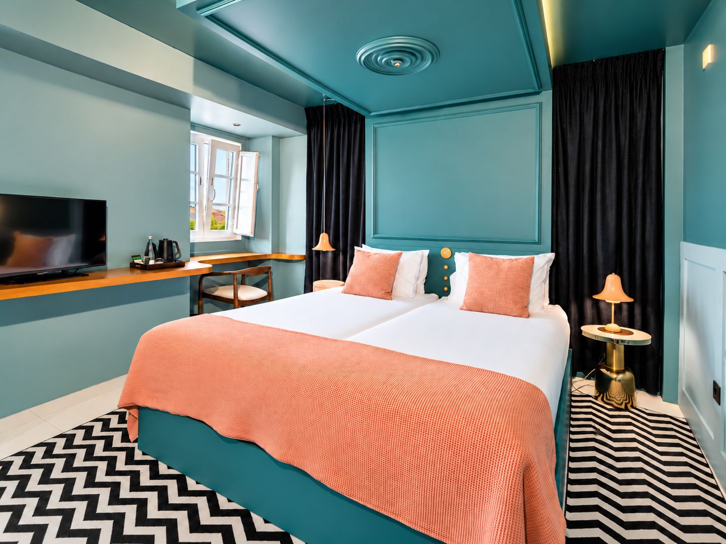 Habitación de hotel moderna con una cama grande, un escritorio, una televisión y vistas al exterior.