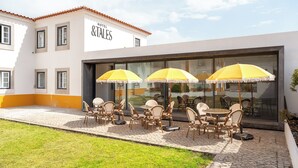 A hotel patio with outdoor seating and umbrellas. - &Tales Hotel (Óbidos)