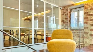 A modern interior with a yellow chair, a staircase, and a brick wall. - &Tales Hotel (Óbidos)