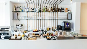 A bar area with shelves of liquor bottles, glasses, and a coffee machine. - &Tales Hotel (Óbidos)