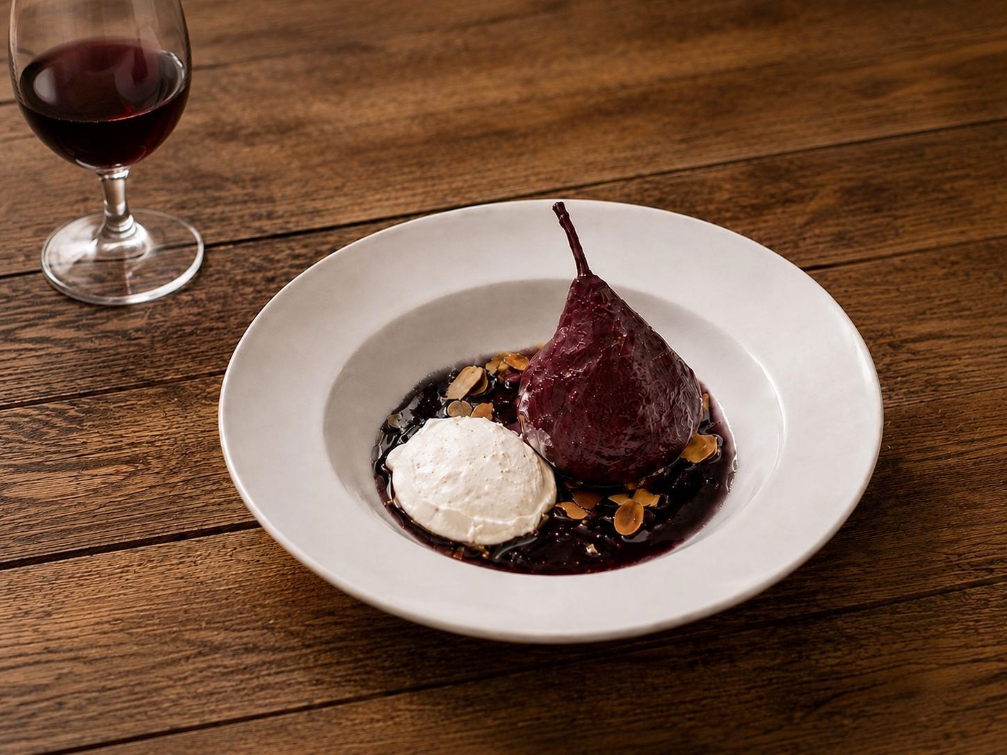 A plate with a pear, a scoop of ice cream, and a dark sauce on a wooden table.
