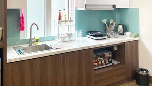 A modern kitchen with a built-in sink, white cabinets, a teal backsplash, and wooden flooring. - Modern apartment with 1 bedroom in West Lake (Hà Nội)