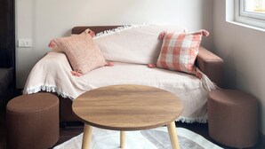 A cozy living room with a sofa, a round coffee table, a floor lamp, and framed artwork on the wall. - Modern apartment with 1 bedroom in West Lake (Hà Nội)
