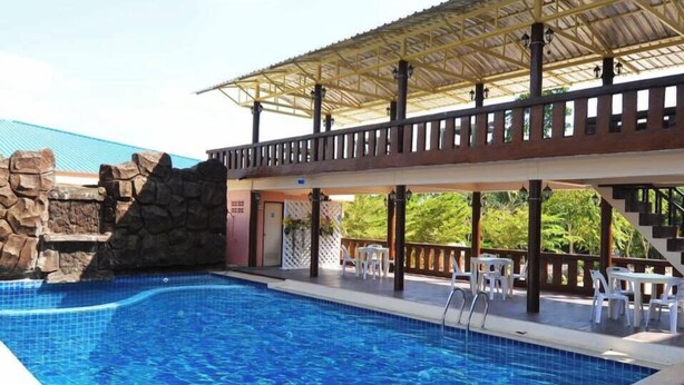 Una piscina amb mur de pedra i zona coberta amb cadires.