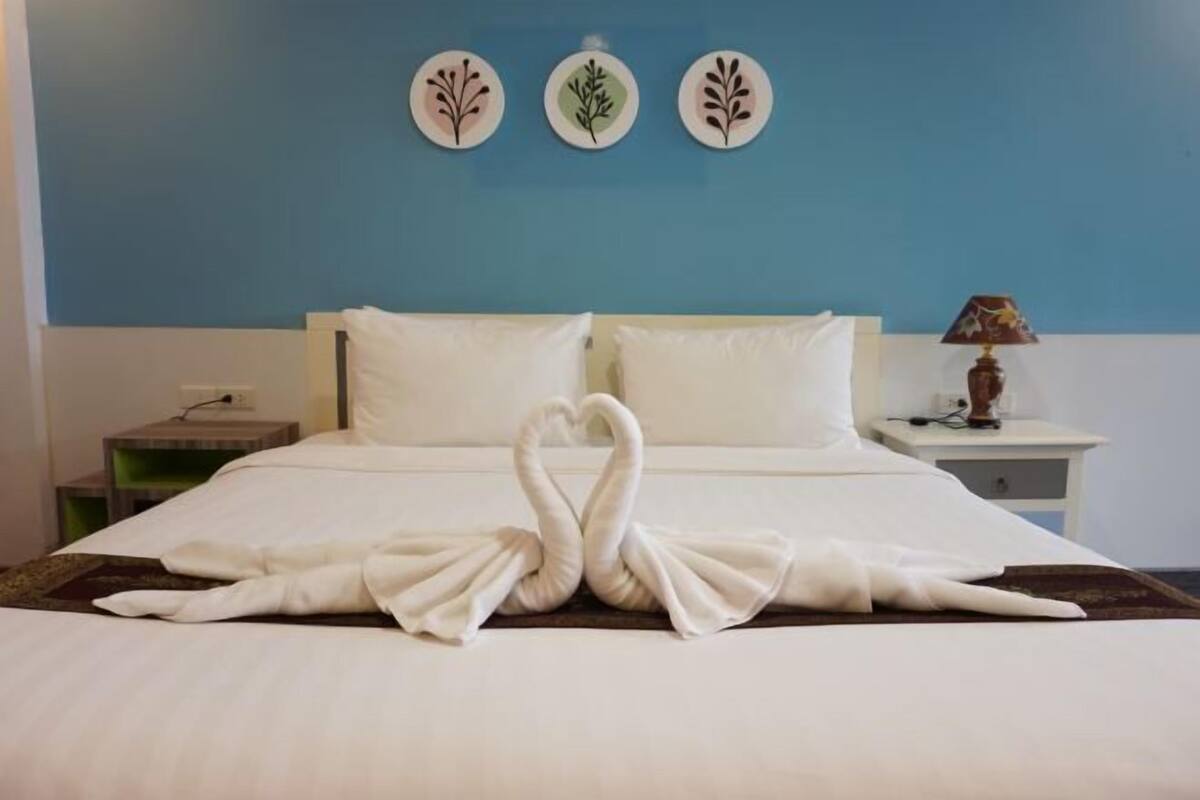 A hotel room with a bed, a nightstand, a lamp, and wall art.
