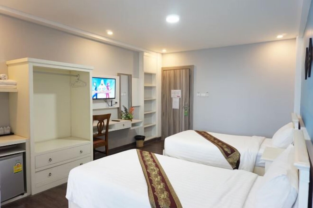 A hotel room with two beds, a desk, a TV, and a wardrobe.