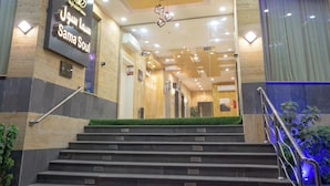 L’entrée d’un hôtel, avec une enseigne indiquant « Sama Souk », et un escalier menant à l’intérieur.