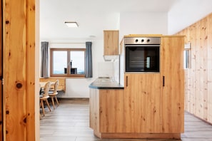 A kitchen with wooden cabinetry, a built-in oven, and a window with curtains.