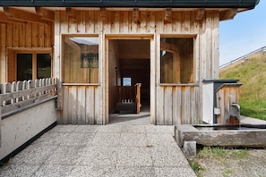 A wooden building with a gravel entrance, a wooden fence, and a small water feature.