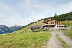 Un chalet in legno con un balcone, un edificio separato e un sentiero sterrato che vi conduce.