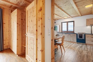 Un interior de madera con una zona de cocina, armarios de madera y una mesa de comedor.
