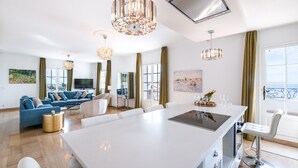 Uma sala de estar moderna com uma ilha central grande, um sofá e uma televisão.