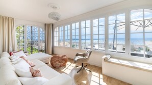 Uma sala de estar ampla com uma grande janela com vista para a paisagem urbana e o mar.