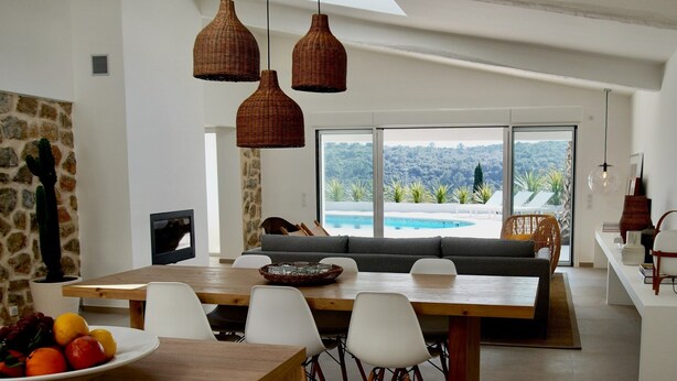 A modern dining area with a wooden table, white chairs, and a large window overlooking a pool and greenery. - Villa Arte – Modern villa in Biot with private pool (Biot)