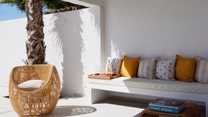 A sunlit outdoor seating area with a wicker chair, a white sofa with patterned cushions, and a tray with glasses and a bottle. - Villa Arte – Modern villa in Biot with private pool (Biot)