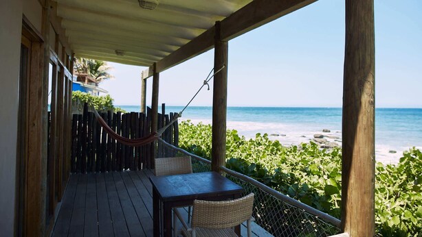 Una terraza de madera con una mesa y sillas con vista a la playa.