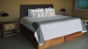 Quarto com cama grande, mesa de cabeceira, ar-condicionado fixado na parede e ventilador de teto.