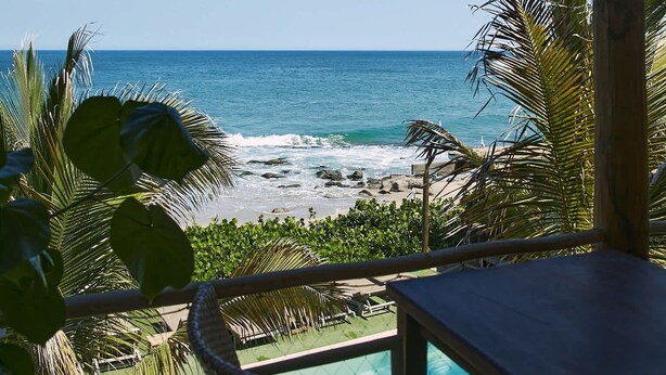 Espaço coberto ao ar livre com vista para o oceano, piscina e área de estar.