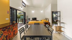 Una habitación moderna con una mesa de comedor, dos camas, un televisor y un estante pequeño.
