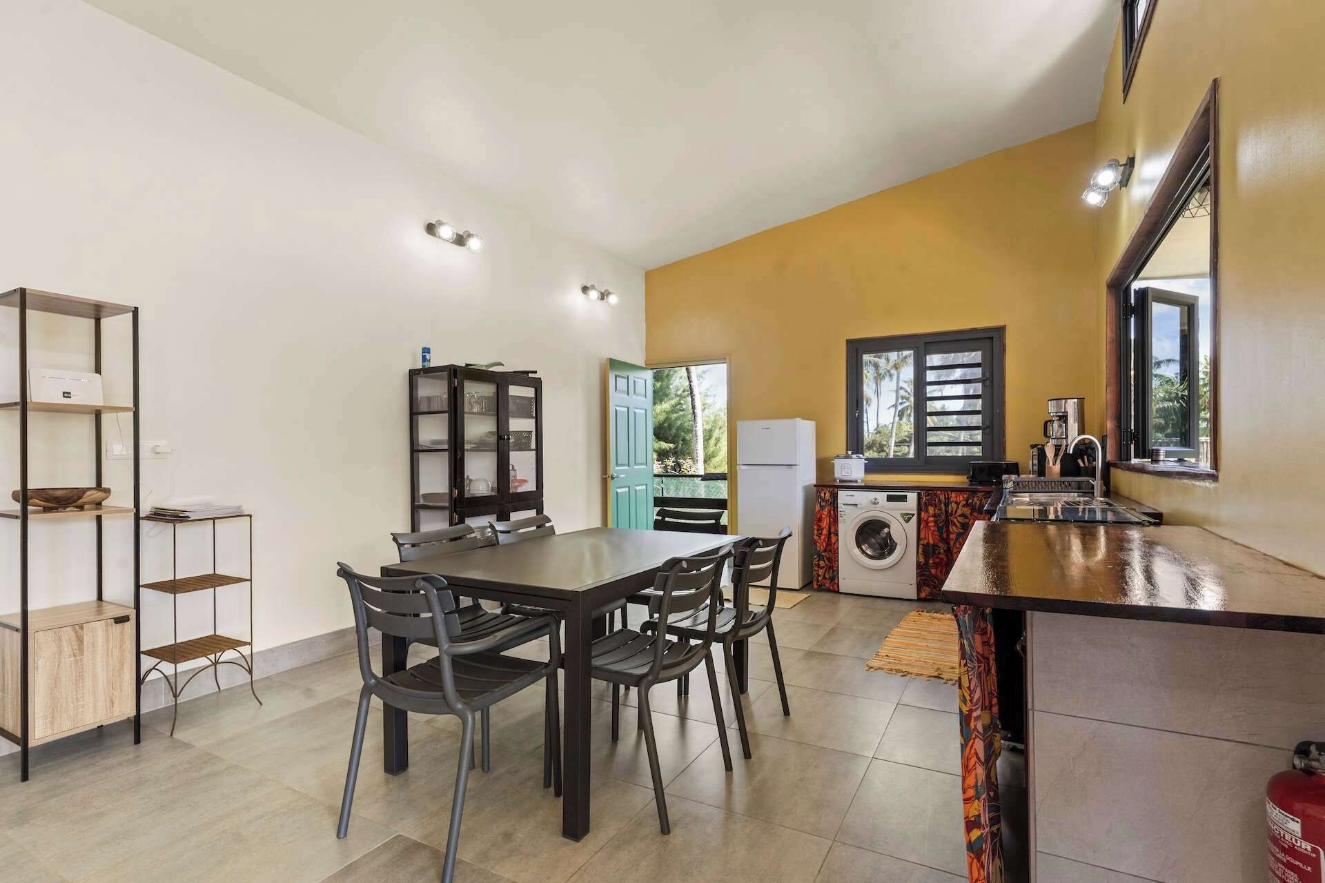 Una cocina compacta con comedor, lavadora y refrigerador.