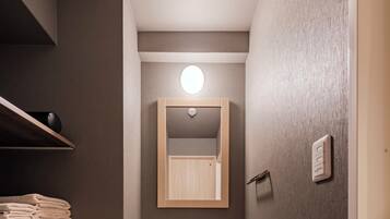 A modern bathroom with a large sink, a mirror, and a shelf with folded towels.