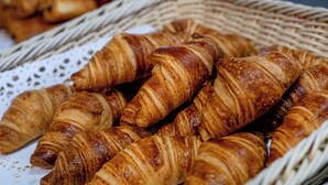 A basket filled with golden-brown croissants. - Rosalita Hostel (Lourdes)