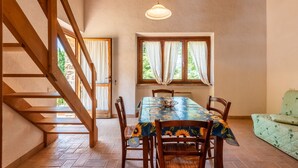 Un espace repas comprenant une table, des chaises, un lustre et un escalier.