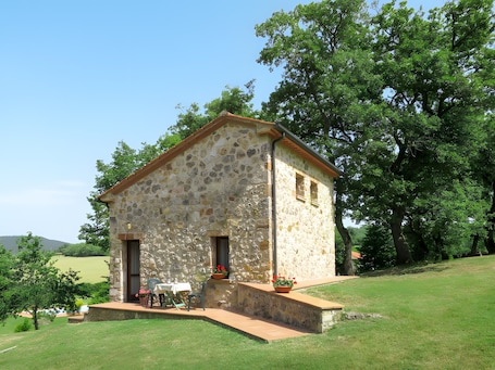 A stone building with a sloped roof, a small porch, and a table with chairs outside.. Holiday Home 'San Michele - Capanna Scopi' with Mountain View, Wi-Fi and Air Conditioning