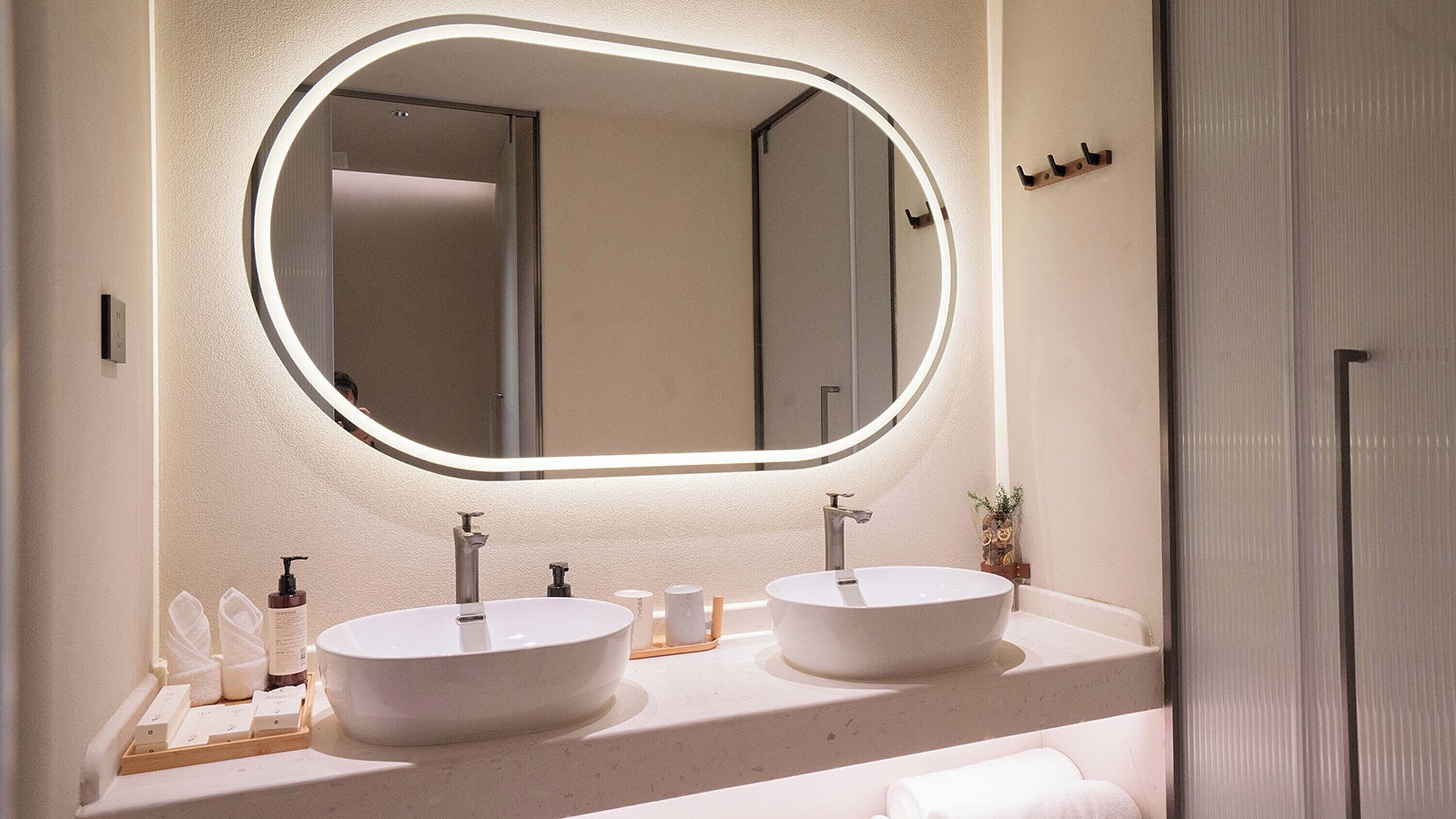 Une salle de bain avec deux lavabos, un grand miroir et un porte-serviettes.
