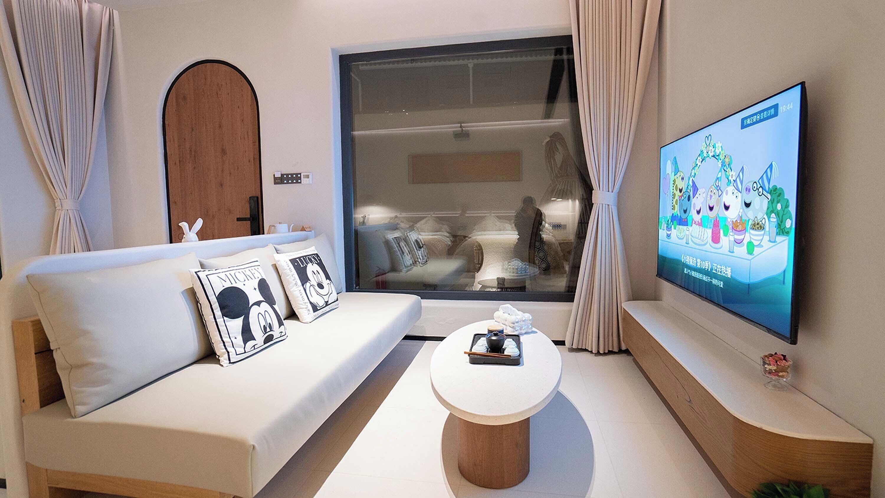 A modern living room with a sofa, a coffee table, and a TV displaying animated characters.
