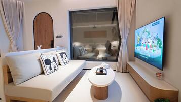 A modern living room with a sofa, a coffee table, and a TV displaying animated characters.