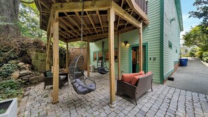 A covered outdoor seating area with wicker furniture and a swing chair. - Inman Park Terrace Suite w/ Private Entrance (Atlanta)
