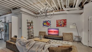 A modern living room with a sofa, a coffee table, a TV, and artwork on the wall. - Inman Park Terrace Suite w/ Private Entrance (Atlanta)