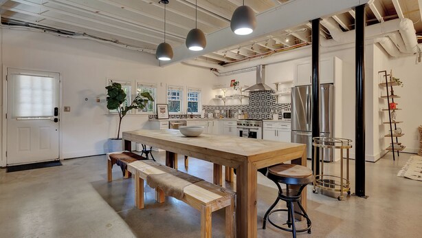 A modern kitchen with a large island, pendant lights, and a dining area with benches. - Inman Park Terrace Suite w/ Private Entrance (Atlanta)