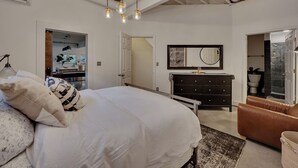A bedroom with a large bed, a dresser, a brown leather chair, and a chandelier. - Inman Park Terrace Suite w/ Private Entrance (Atlanta)
