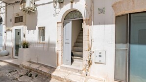 A building with a staircase leading to an upper floor, a door with a metal handle, and a window with a metal grill. - Dimora Oliver by Rentbeat  (Ostuni)