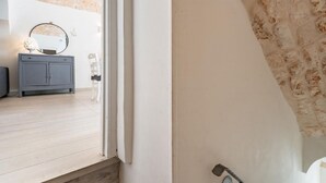 A room with a white wall, a grey cabinet, a round mirror, and a white chair. - Dimora Oliver by Rentbeat  (Ostuni)